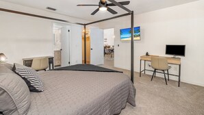 Un dormitorio con cama, escritorio, silla y ventilador de techo.