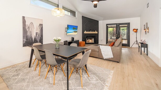 Una sala moderna con chimenea, un comedor con mesa y sillas, y un sofá.