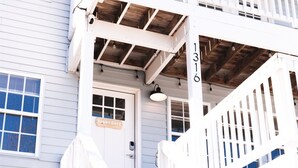 A white wooden staircase leading to a porch with a sign that reads "Sunny Days." - Walk to Beach | Luxe Home W/ Backyard, Gym, Office (Carolina Beach)