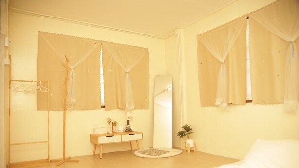 A bedroom with a bed, a bedside table, a mirror, a dresser, and a window with sheer curtains. - Friend's House Arak  (Chiang Mai)