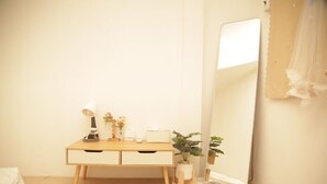 A bedroom with a wooden desk, a mirror, a bedside plant, and a bed with a striped pillow. - Friend's House Arak  (Chiang Mai)