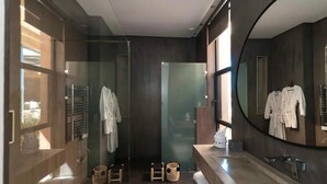 Une salle de bain moderne avec une douche à parois de verre, un grand miroir et un meuble-lavabo.