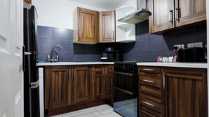 Une cuisine moderne avec des meubles en bois, un four encastré, un four à micro-ondes et un évier.