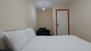 Une chambre à coucher avec un lit, une chaise et une porte.