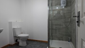 Une salle de bain comprenant des toilettes, un espace douche et un lavabo.