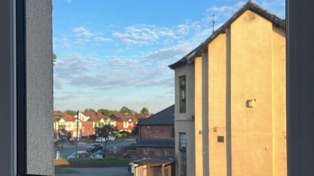 Une fenêtre donnant sur un quartier résidentiel, avec vue sur des maisons et une rue.