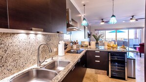 A modern kitchen with granite countertops, stainless steel appliances, and a built-in wine cooler. - CABO PENTHOUSE CONDO - Rooftop deck with Private Jacuzzi at Puerta Cabos Village (Cabo San Lucas)