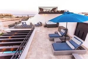 A rooftop terrace with a pool, lounge chairs, and a hot tub.