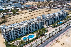 A multi-story hotel with a rooftop pool area and a landscaped pool.