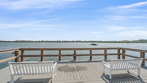 Een houten pier met twee witte banken die uitkijken op een rustig wateroppervlak.
