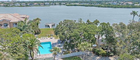 A large swimming pool surrounded by lush greenery and a view of a lake.