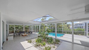 A modern outdoor space with a pool, seating area, and a view of the surrounding greenery. - Gorgeous Mid-Century Modern Pool Home on Private Canal, Mins to Siesta Key Beach (Siesta Key)