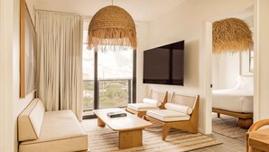 A modern living room with a sofa, two armchairs, a coffee table, and a TV.