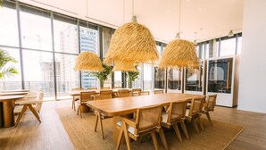 Un vaste espace dédié à la salle à manger, avec une grande table et des chaises en bois, le tout entouré de grandes fenêtres offrant une vue sur le paysage urbain.
