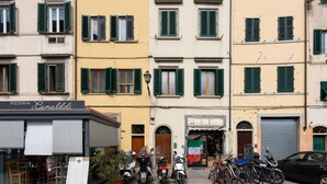 Una filera d'edificis d'alguns pisos amb persianes verdes, una pizzeria i scooters i bicicletes aparcades.
