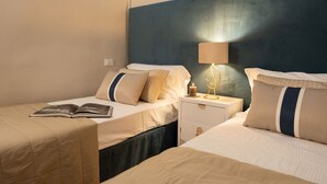Habitació d'hotel amb dos llits, una tauleta de nit amb una làmpada, i un llibre al llit esquerre.