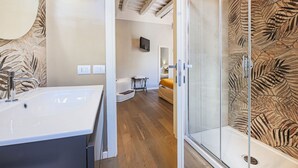 A bathroom with a large sink, a glass shower enclosure, and a wooden leaf-patterned wall. - Fiesolana's Flower with balcony (Firenze)