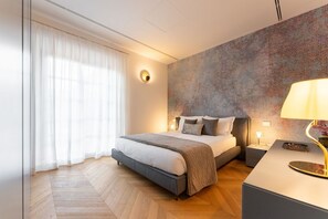 A modern bedroom with a large bed, a bedside table, a nightstand, a wall-mounted lamp, and a patterned wall. - Modern Florentine Terrace (Florence)