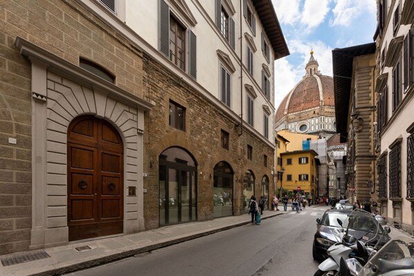 A street with historic buildings, a prominent dome, and parked cars.