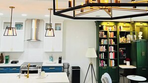 A modern kitchen with white cabinets, a central island, and pendant lighting. - Cozy stay in Mission - With Pool & Patio (Mission)