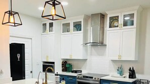 A modern kitchen with white cabinets, a central island with stools, and pendant lighting. - Cozy stay in Mission - With Pool & Patio (Mission)