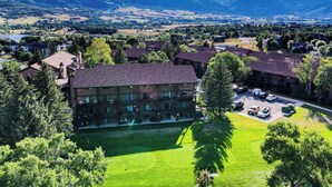 Een meerlaags hotel met een centrale binnenplaats, omringd door weelderige begroeiing en bergen op de achtergrond.