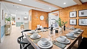 A dining area with a long wooden table set for a meal, surrounded by chairs. - 4br 3ba / 10 min to NRG / hot tub / sauna / firepit (Oak Hill)