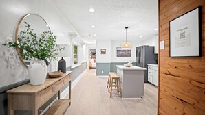A modern kitchen with a wooden island, a large mirror, and a welcoming sign. - 4br 3ba / 10 min to NRG / hot tub / sauna / firepit (Oak Hill)