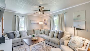 Ein Wohnzimmer mit Ecksofa, Couchtisch und Deckenventilator.