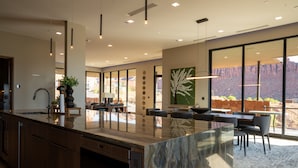 Una cocina moderna con una isla grande, electrodomésticos integrados y ventanas amplias con vistas al exterior.