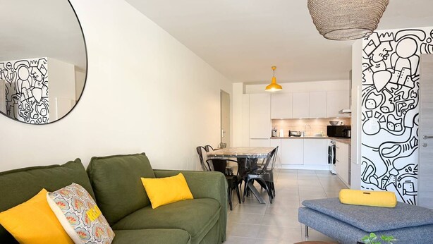A modern living room with a green sofa, a dining table, and a kitchen in the background. - BEL'ORIZONTE - Two rooms near the sea (T) (PROPRIANO)