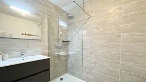 A modern bathroom with a glass shower enclosure, a white sink, and a dark vanity. - BEL'ORIZONTE - Two rooms near the sea (T) (PROPRIANO)