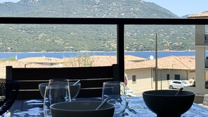 A dining table with bowls and glasses, overlooking a mountainous landscape and a body of water. - BEL'ORIZONTE - Two rooms near the sea (T) (PROPRIANO)