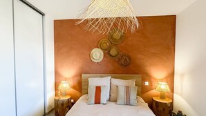 A bedroom with a large bed, two bedside tables with lamps, a woven ceiling light fixture, and decorative wall hats. - BEL'ORIZONTE - Two rooms near the sea (T) (PROPRIANO)