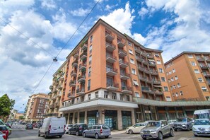 A multi-story residential building with balconies, a parking area, and a clear sky. - Appartamento con 3 camere e terrazzo a 500 mt dalla stazione (Verona)