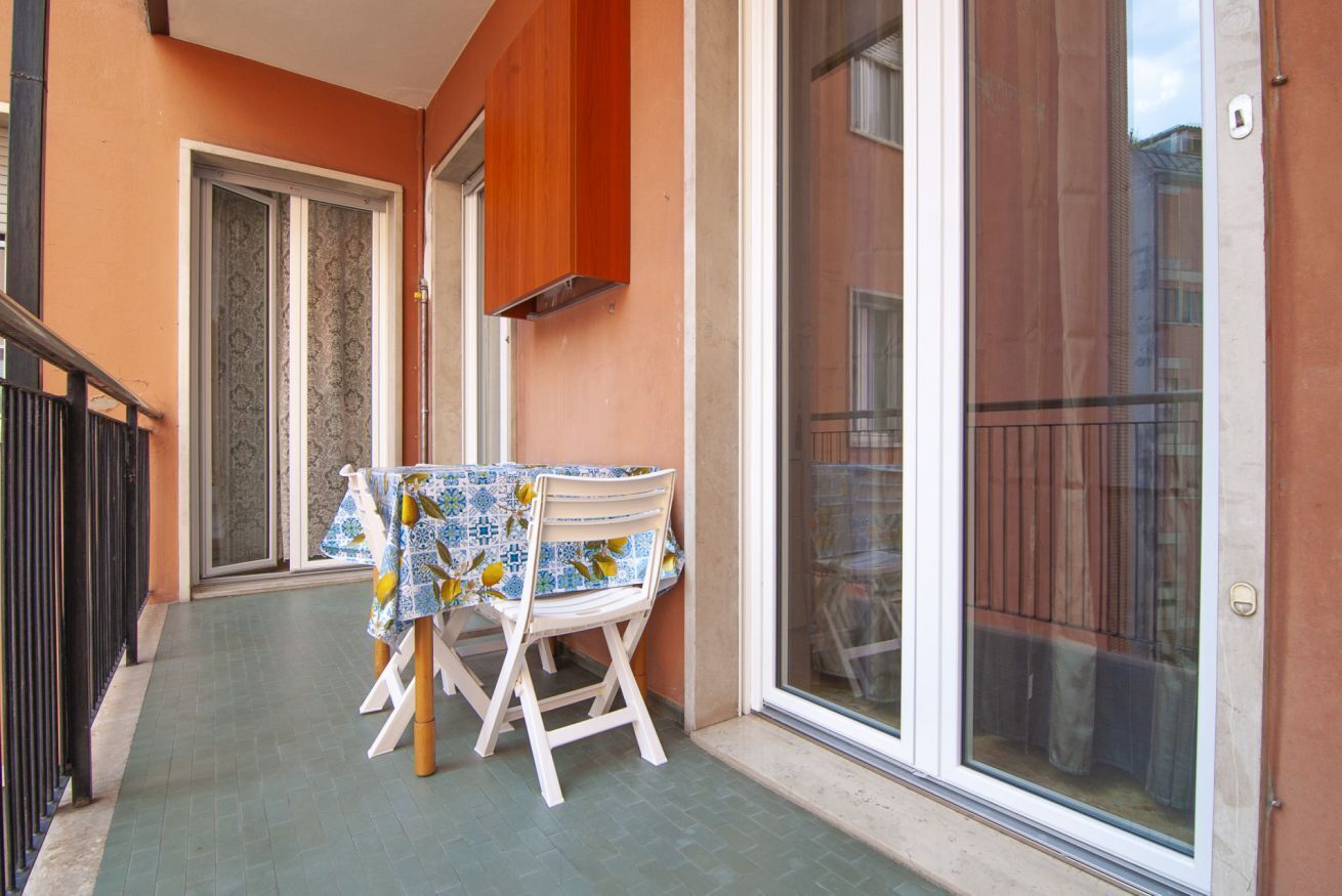 Ein Balkon mit Tisch und Stühlen, einer Schiebetür und einem Holzgeländer.