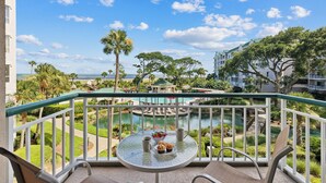 A balcony with a glass table, chairs, and a view of a pool and ocean. - 4205 Windsor @ Palmetto Dunes | Oceanfront Villa | Pool & Spa | Moments to Beach (Hilton Head Island)