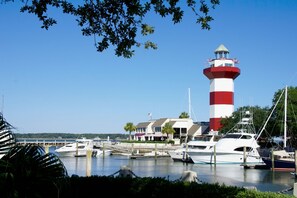 A marina with a prominent lighthouse, boats docked, and a building with a red and white striped tower. - 2BR Palmetto Dunes Villa, 2 Oceanfront Pools, Kids Pool & Boardwalk to Beach (Hilton Head Island)