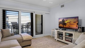 A living room with a sofa, a TV, and a cabinet. - Castle Reef 428 - Lovely location on No drive Beach (New Smyrna Beach)