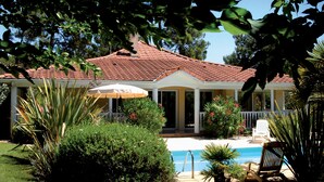 Una casa con techo de tejas rojas, un porche cubierto y una piscina.