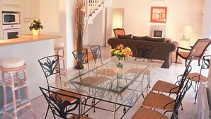 Una sala moderna con una mesa de comedor de cristal, sillas de metal, un sofá y una escalera.