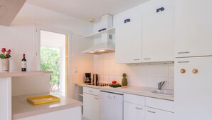 Une cuisine moderne avec des meubles blancs, un plateau jaune et une machine à café.