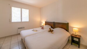Une chambre d’hôtel avec un lit double, des lampes de chevet, une table de chevet, une fenêtre et un radiateur.
