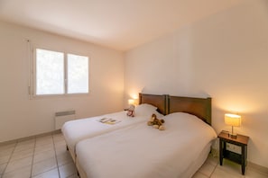 Une chambre d’hôtel avec un lit double, des lampes de chevet, une table de chevet, une fenêtre et un radiateur.