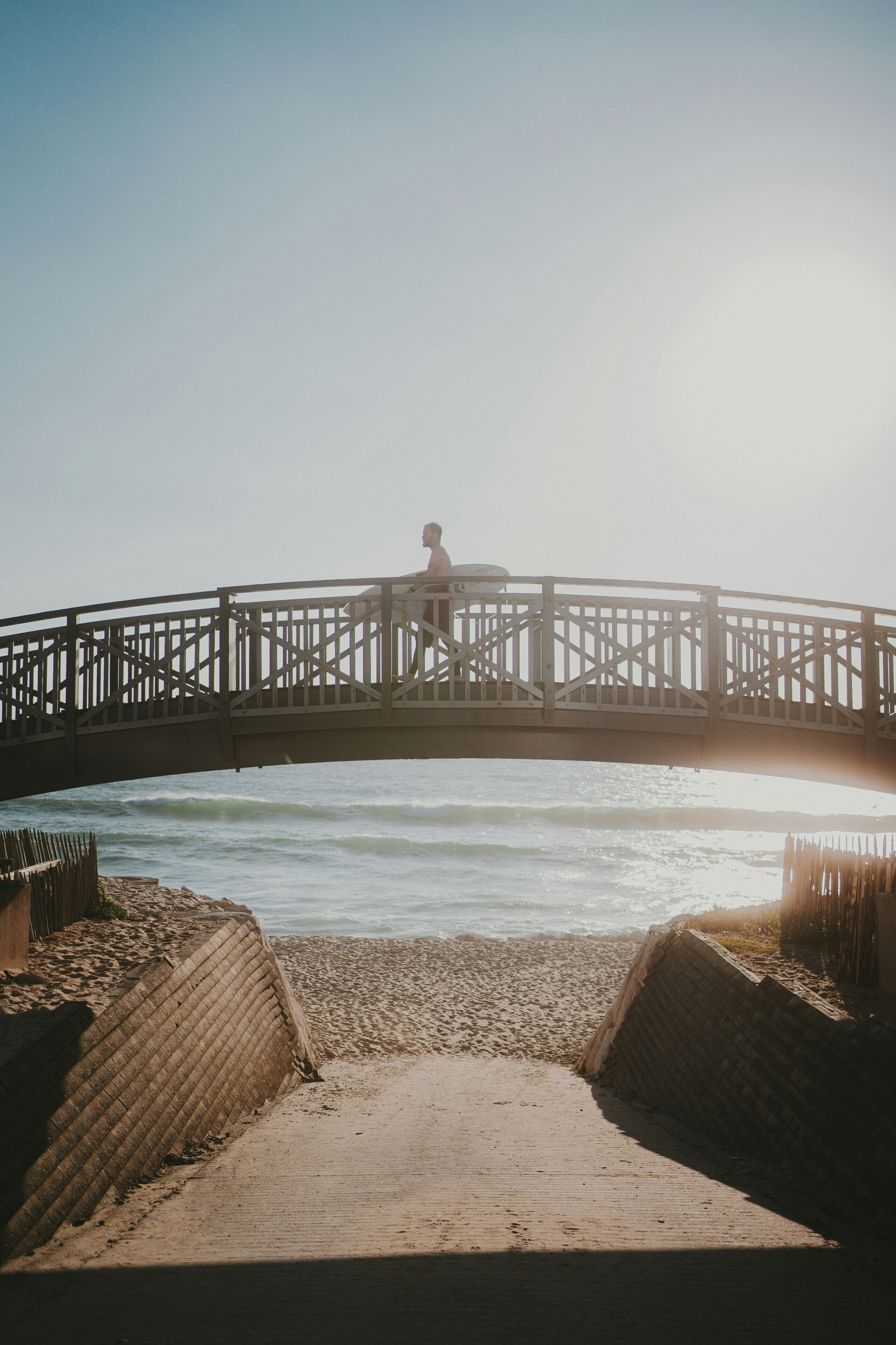 Un puente de madera sobre una playa, con una persona caminando.