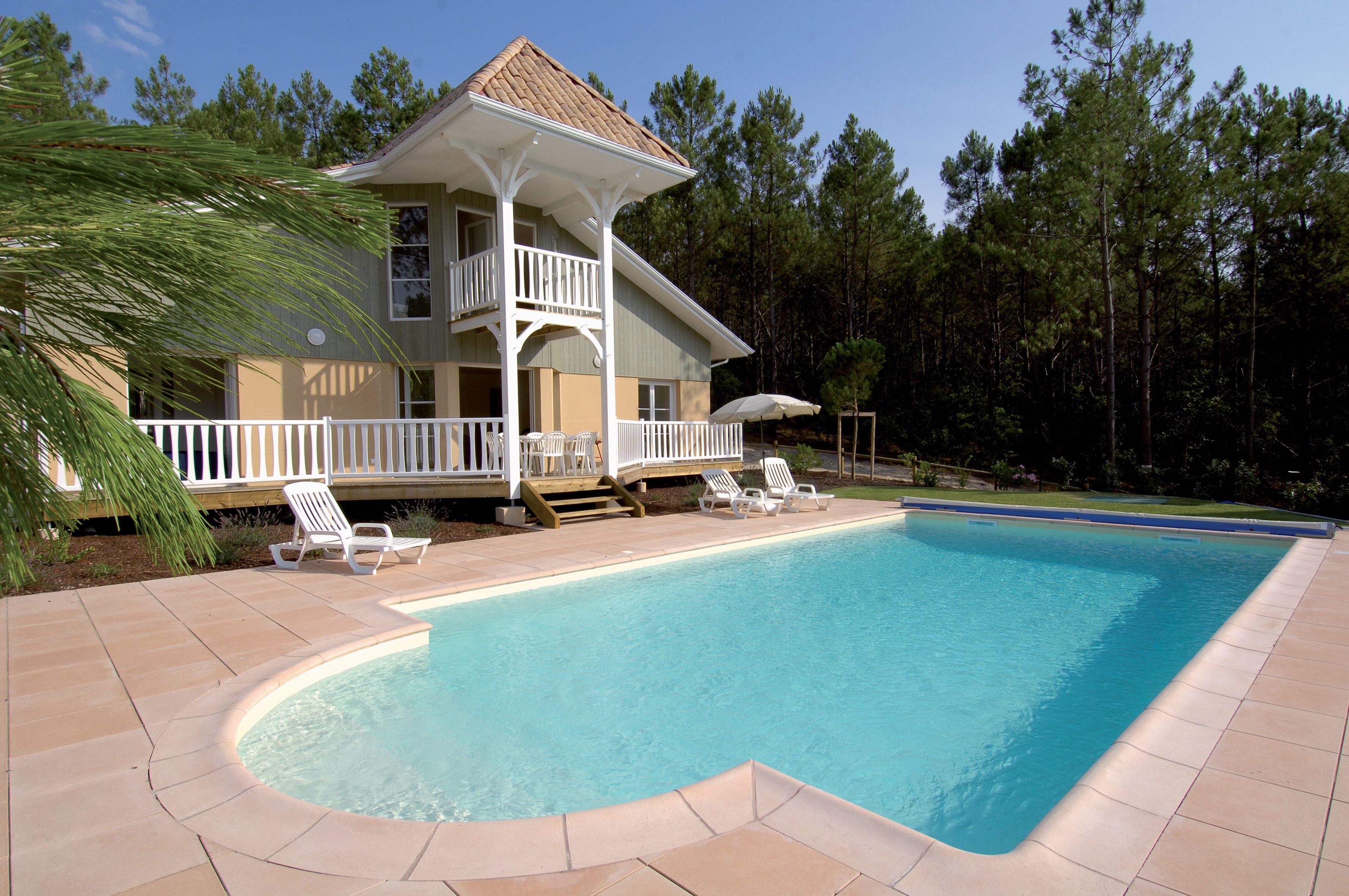 A two-story house with a pool, a covered deck, and a wooden deck leading to the pool.