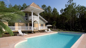 A two-story house with a pool, a covered deck, and a wooden deck leading to the pool. - À 3,5 km des plages de Lacanau | Villa + piscine (Lacanau​)
