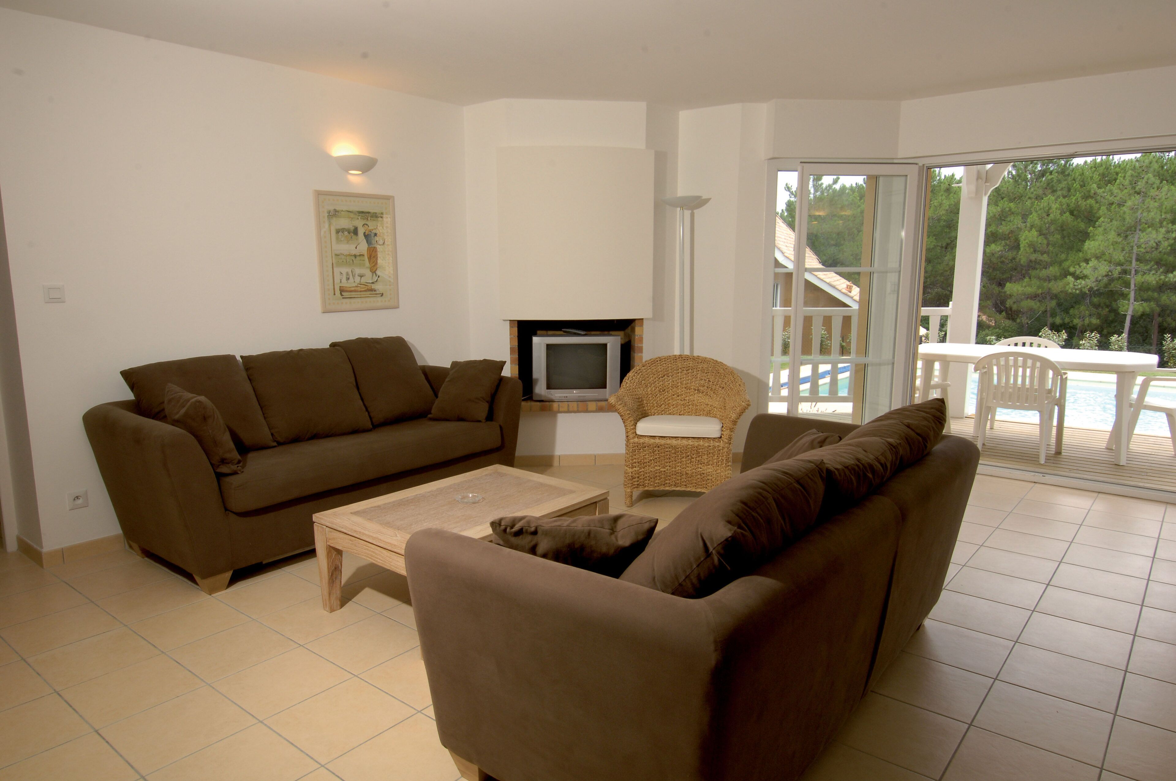 A living room with a brown sofa, a small television, and a wicker chair.