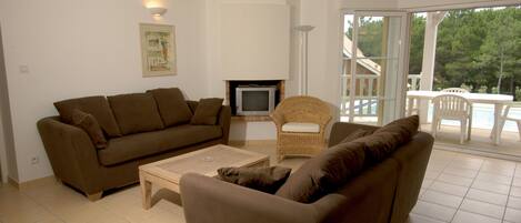 A living room with a brown sofa, a small television, and a wicker chair.