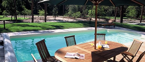 Une terrasse en bois avec une piscine, entourée d’arbres.